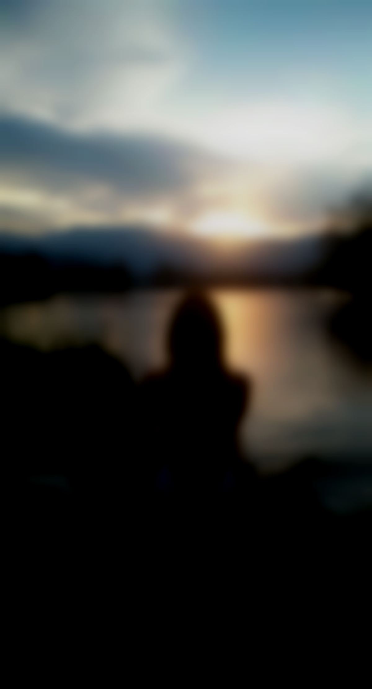 cette femme assise au bord du lac d'annecy vu de dos, en maillot de bain, regardant le couché de soleil.