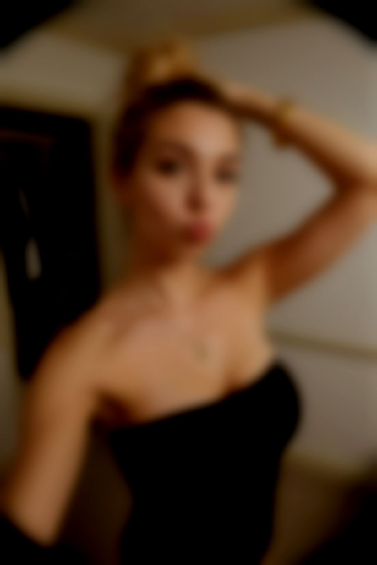 A beautiful young woman standing in a bedroom, slowly pulling her strapless top down to expose her bare breasts.